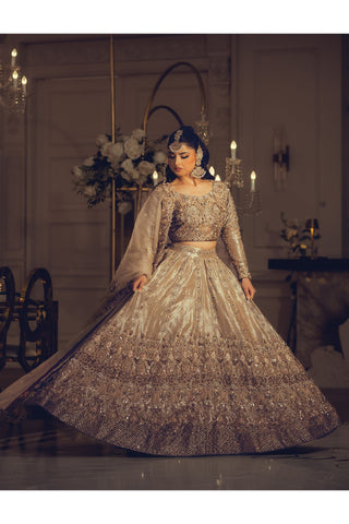 Woman in an ornate dress standing in a decorated room with chandeliers and tables.