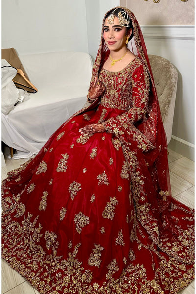 Woman in a red and gold traditional outfit sitting on a couch.